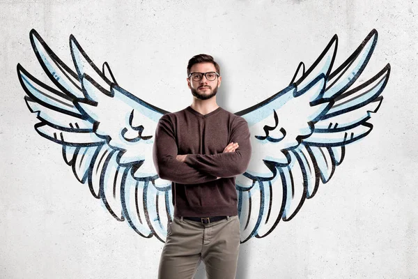 Man with glasses wearing casual clothes with wings drawn on the wall on the background