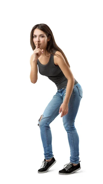 Юная брюнетка в джинсах и футболке с безмолвным жестом на белом фоне — стоковое фото