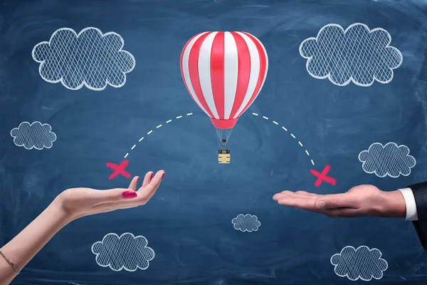 Man en vrouw open handpalmen klaar om te vangen een luchtballon tegen een blauwe schoolbestuur met wolken van krijt. — Stockfoto