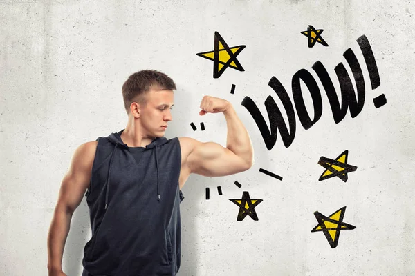 Сильний м'язистий молодий чоловік показує біцепси зі знаком WOW і кричить зірки, намальовані на фоні білої стіни — стокове фото
