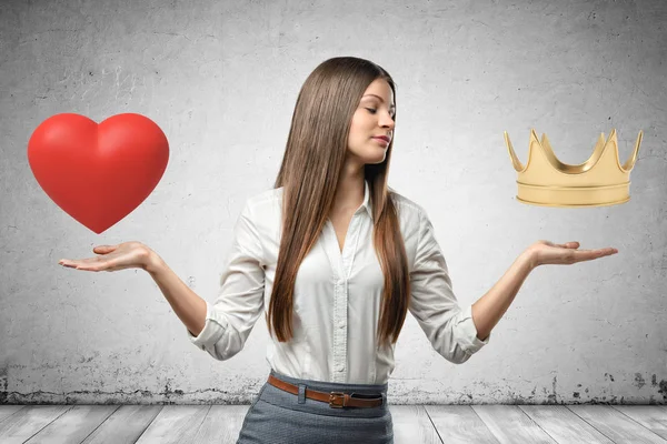 Jeune femme d'affaires tenant coeur rouge et couronne dorée dans ses mains sur fond de mur gris. contexte — Photo