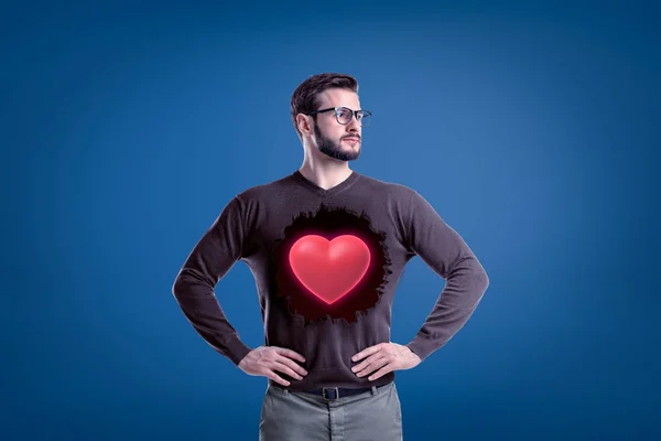 Homme avec des lunettes et un coeur rouge sur un pull gris sur fond bleu — Photo