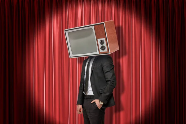 Businessman with vintage tv set instead of head on red stage curtains background — Stock Photo, Image