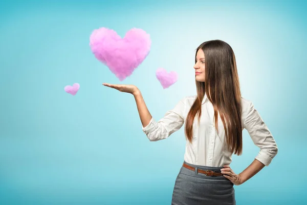 Jeune femme d'affaires tenant coeur nuage rose sur sa main sur fond bleu — Photo
