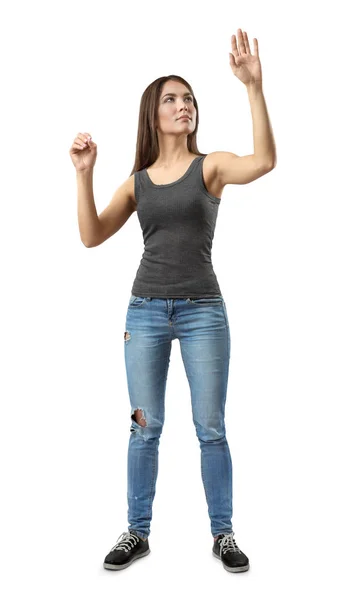 Young woman in gray top and blue jeans standing, one hand in pinch gesture and other raised as if touching invisible glass isolated on white background. — 스톡 사진