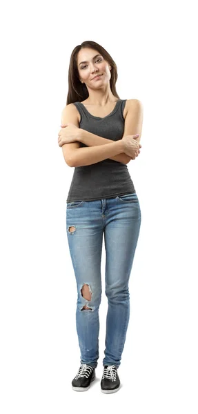 Junge Frau in grauem ärmellosen Oberteil und blauer Jeans mit verschränkten Armen auf weißem Hintergrund. — Stockfoto