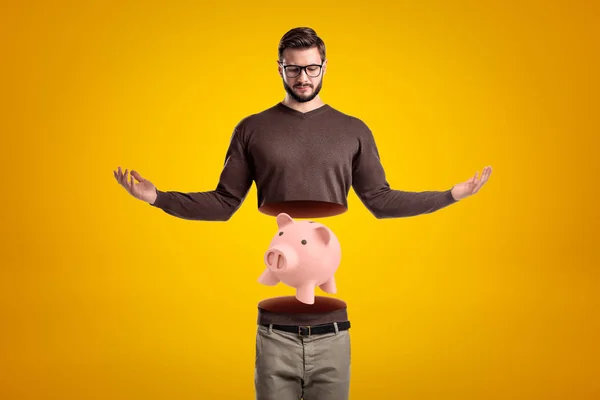 Jonge man in Casual kleding in tweeën gesneden met roze Piggy Bank binnen op gele achtergrond — Stockfoto