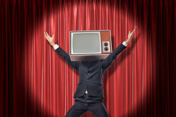 Empresário feliz com vintage tv set em vez de cabeça levantando braços em vermelho palco cortinas fundo — Fotografia de Stock