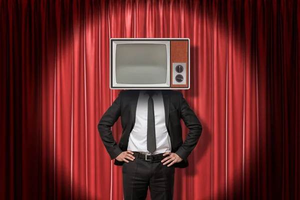 Empresário com vintage tv set em vez de cabeça em vermelho palco cortinas fundo — Fotografia de Stock
