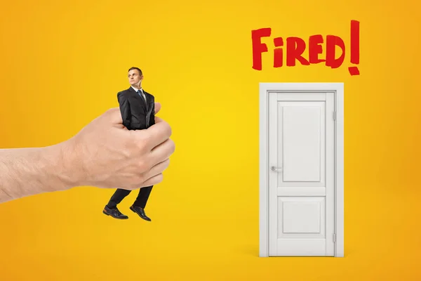 Nagy férfi kézzel hozza kis üzletember, hogy fehér ajtón, piros tüzelt jel sárga háttér — Stock Fotó