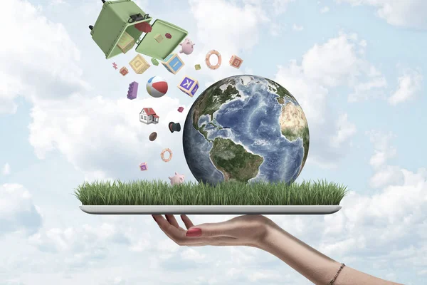 Womans hand holding tablet with grass and little planet Earth on screen, and trash can in air dumping out various objects down on Earth.
