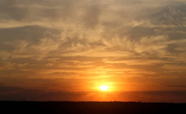 Bella foto di un tramonto luminoso con nuvole su un campo — Foto Stock