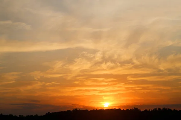 Bella foto di un tramonto luminoso con nuvole su un campo — Foto Stock