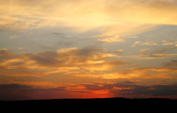 Bella foto di un tramonto luminoso con nuvole su un campo — Foto Stock