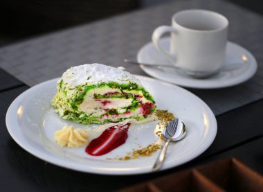 Bir kafede bir plaka üzerinde parlak bir fıstık kremalı pasta fotoğrafı