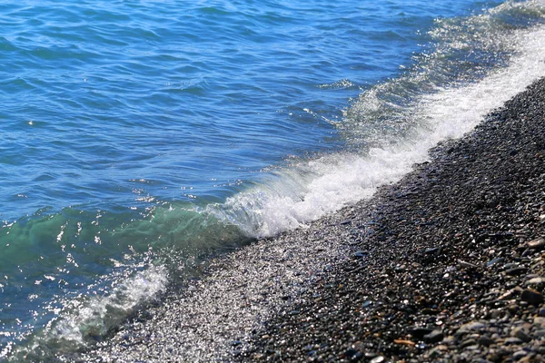Makro fotoğraf mavi deniz dalgalarının sahilde köpük ile