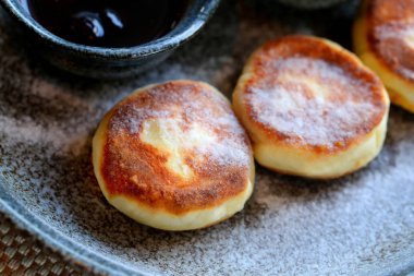 Makro fotoğraf lezzetli parlak peynir kek ile reçel ve ekşi krema bir restoranda karanlık bir plaka üzerinde