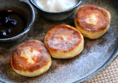 Makro fotoğraf lezzetli parlak peynir kek ile reçel ve ekşi krema bir restoranda karanlık bir plaka üzerinde