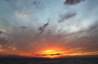 Sonbaharda akşam vakti denizin üzerinde bulutlarla güzel bir gün batımı fotoğrafı.