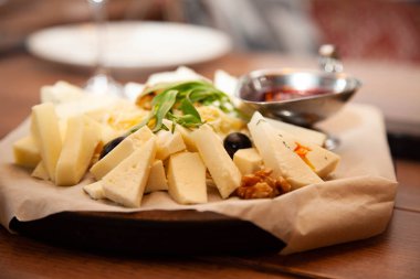 Ahşap masa üzerinde yeşil yaprakları ve sosu ile lezzetli peynir tabağı yakından görünümü