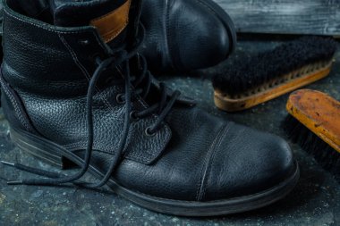 Ahşap arka plan üzerinde ayakkabı fırçası ile eski vintage deri çizmeler