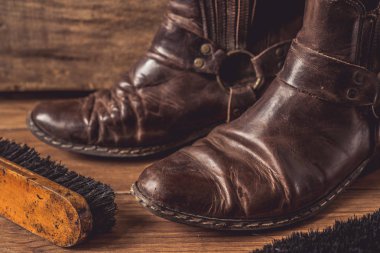 Ahşap arka plan üzerinde ayakkabı fırçası ile eski vintage deri çizmeler