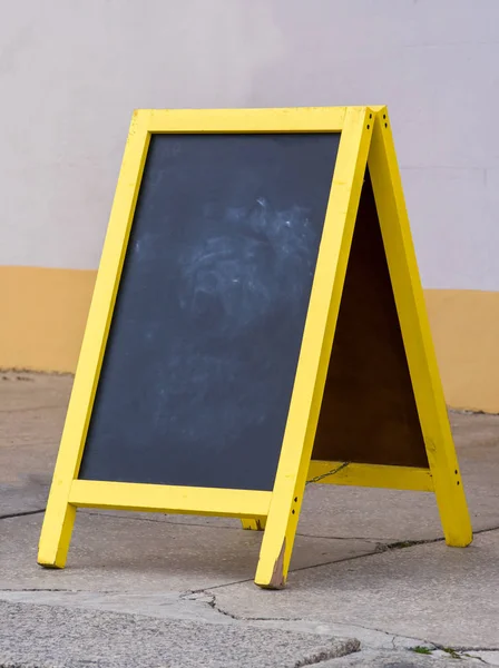 Wooden rustic blackboard in front of restaurant entrance