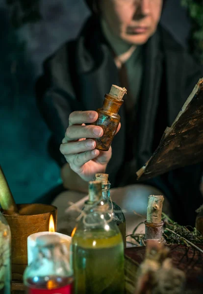 Dark Witch at work: black magic woman makes the witchery by mixing herbs, casting the spells, running magic rituals