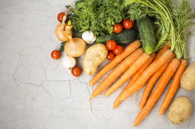 Organik sebze hasat ile havuç, domates, salatalık, soğan, patates gri arka planda, üstten görünüm