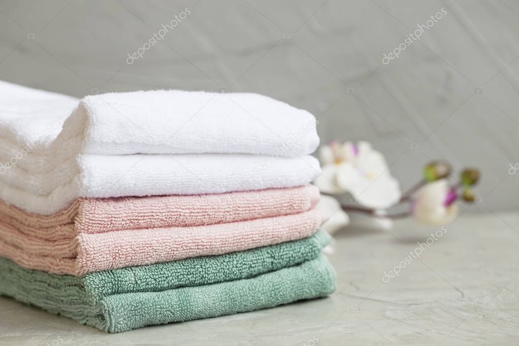 Pile of clean cotton bath towels on concrete background, laundry or bathroom concept