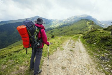 Uzun yürüyüşe çıkan kimse sırt çantası, trekking sopa ile bir dağ yolu