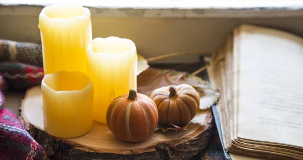 Fall decorations with candles and pumpkins with a book and blanket, cozy still life