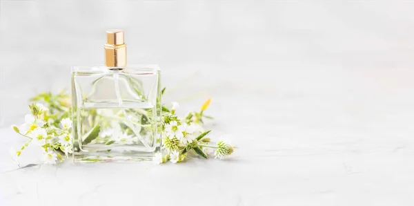 Perfume bottle with white flowers and copy space, white floral scent perfume in transparent bottle