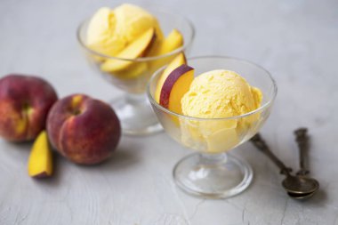 Şeftalilerin olduğu bardak beton zemin üzerine dondurma. Lezzetli tatlı ferahlatıcı yaz. Meyve dondurma kaşık toz