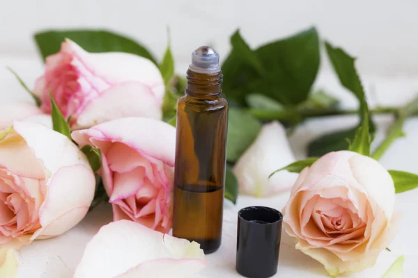 Roses oil perfume in roller bottle with roses flowers, beauty natural rose oil perfume aroma