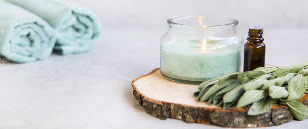 Spa still life set with candle and essential oil bottle,sage oil and cotton towels, wellness and spa clean composition setting, spa therapy products, aromatherapy concept