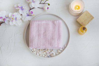 Spa still life setting with cotton towel, oil bottle, natural soap and scented candle, spa orchid flower, top view of spa background