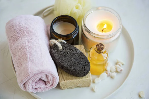 Spa and beauty treatment products  with scented candle, oil, soap, cream and towel, wellness and spa products in a tray, beauty care concept