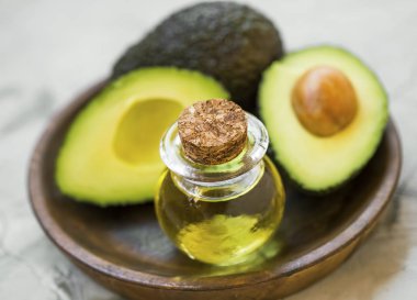 Avokado meyve ahşap plaka, yeşil, aromatik, taze ve sağlıklı yağ içinde halfs şişeyle avokado yağı