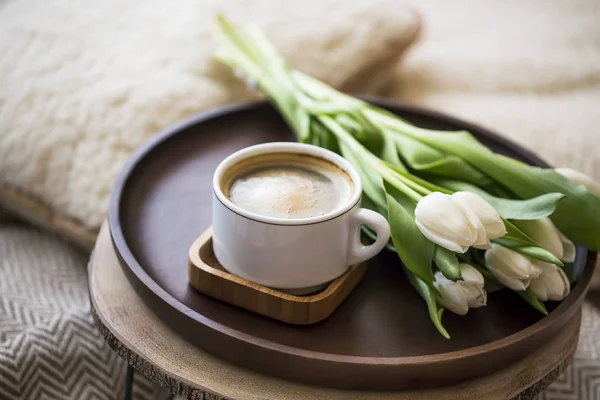 Coffee cup with tulips bouquet in wooden plate, home cozy interior details, cappuccino coffee cup