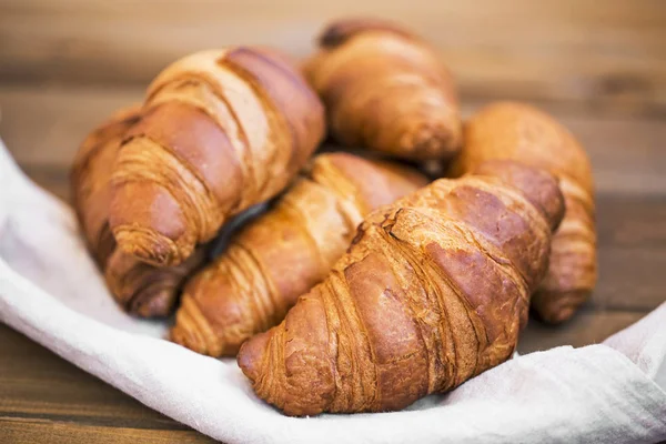 Freshly baked croissants on kitchen napkin on wooden table, fresh french croissants, breakfast buns