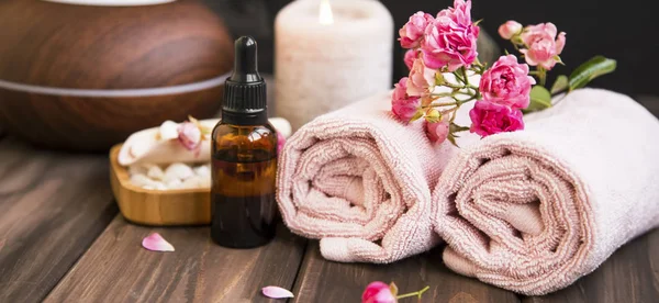 Lázně Zátiší s ručníky, láhev růžového oleje, květy růže na woo — Stock fotografie