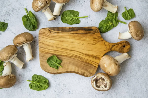 Шампиньонские грибы с листьями шпината и деревянными досками — стоковое фото