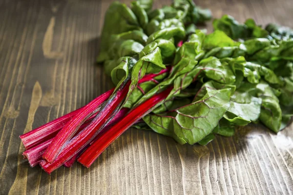 Mangold or red swiss chard leaves on wooden board — Stock Photo, Image