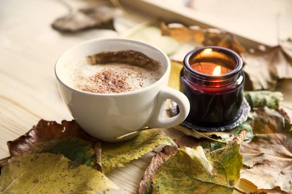Autumn coffee cup with candle and dried leaves decorations on wo — Stock Photo, Image