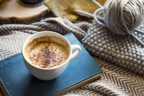 Tazza di caffè autunnale con libro e lana e ferri da maglia, accogliente — Foto Stock