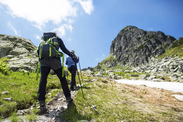 Senderistas con mochilas y bastones de trekking senderismo a la montaña —  Fotos de Stock