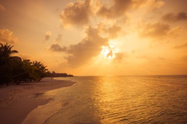Cennet manzarası tropikal ada plajı, gün doğumu çekimi. Sakin tropikal gün batımı plaj manzarası, bulutların üzerinde güneş ışığı. Huzurlu 