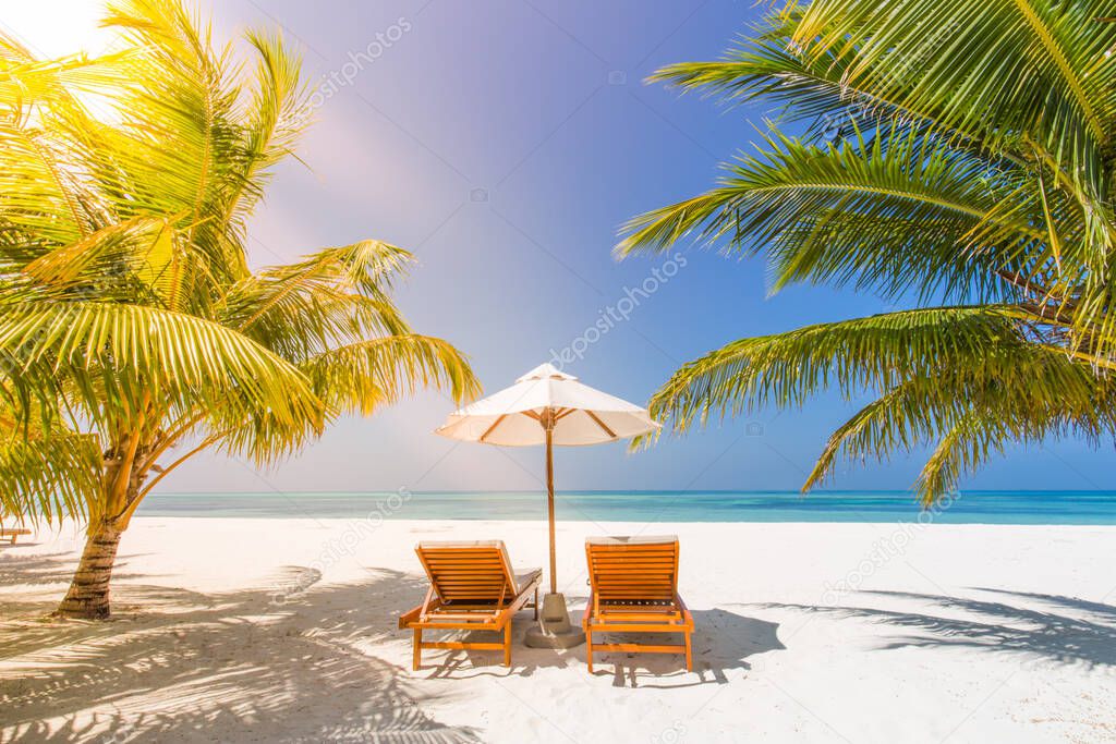 Beautiful tropical sunset scenery, two sun beds, loungers, umbrella under palm tree. White sand, sea view with horizon, colorful twilight sky, calmness and relaxation. Inspirational beach resort hotel landscape