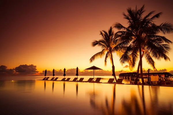 美丽的山坡和日落的天空 奢华的热带海滩景观 甲板椅 躺椅和倒水 夕阳西下的天堂海滩游泳池 可以看到棕榈树 热带风景 异国情调的岛屿酒店 — 图库照片